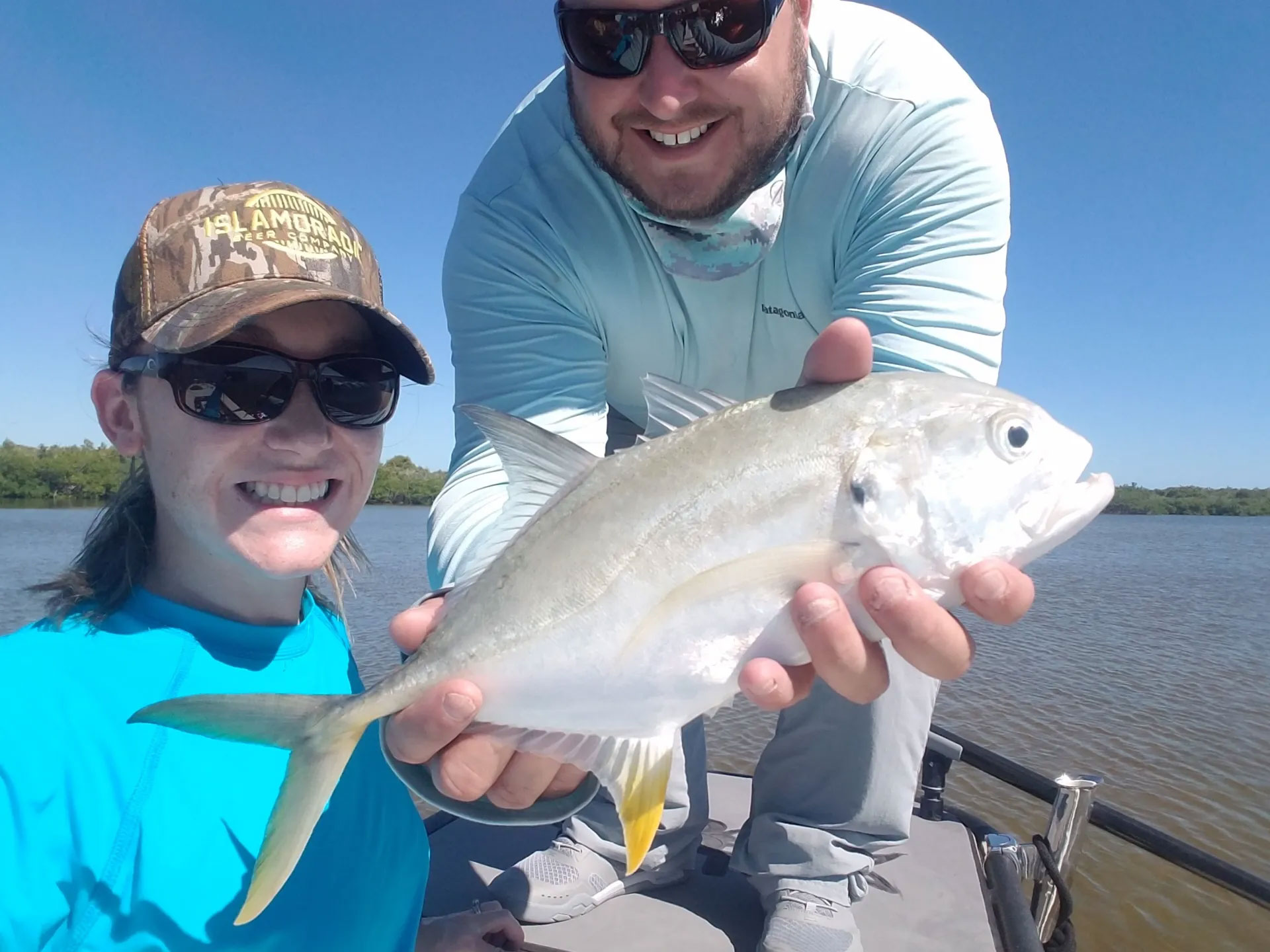 proudly displaying small white fish caught on charter